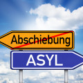Schild mit Wegweiser Rassismus, Toleranz, Abschiebung und Asyl